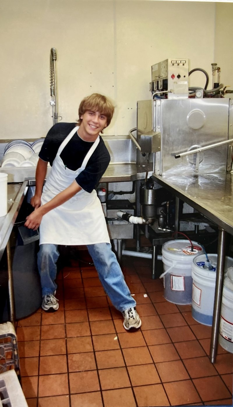 A teenage Alex in an apron at the dish station of the Dinner Bell