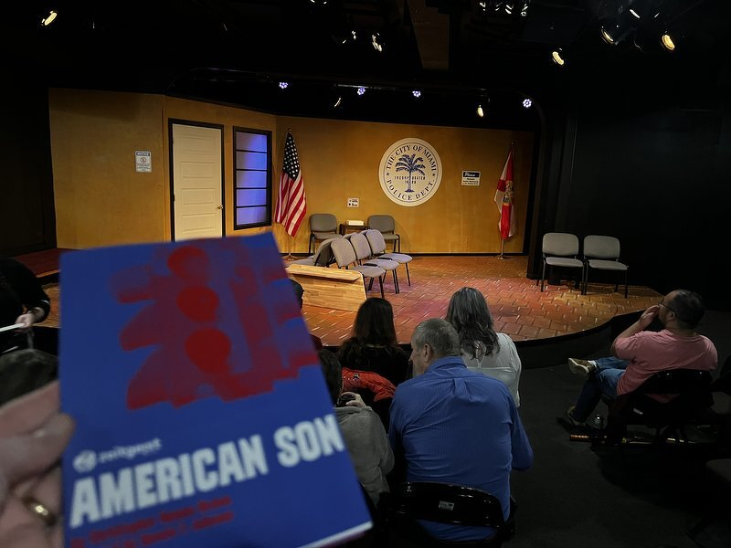 The American Son program held up in front of the Zeitgeist stage, dressed as a Miami police station with flags and a city seal on the wall