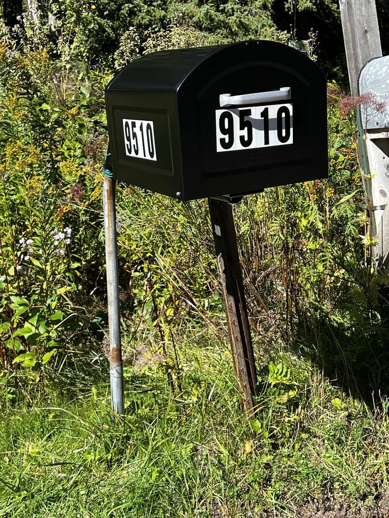 The new oversized black mailbox on its swinging arm at the side of the road