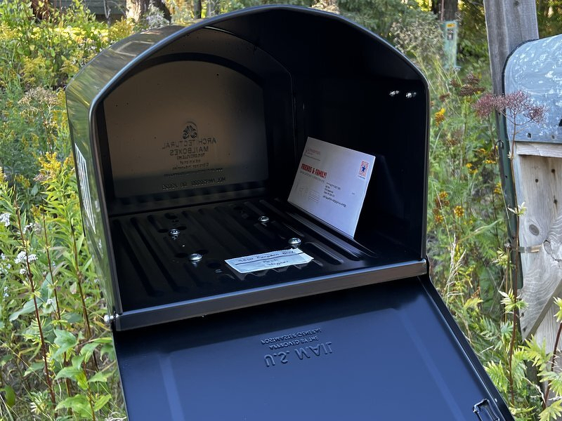 The new mailbox with its door hanging open, a single envelope inside and an enormous amount of room to spare