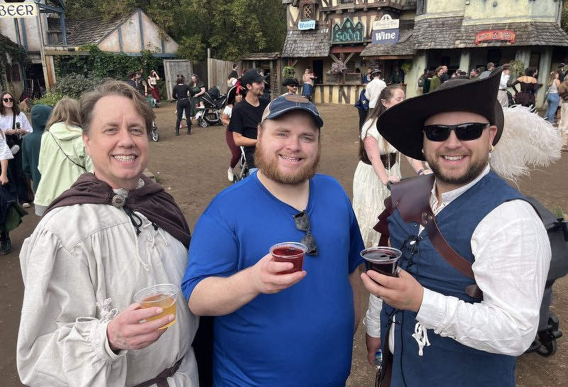 Three of us holding mead in front of the festival's timbered shop fronts