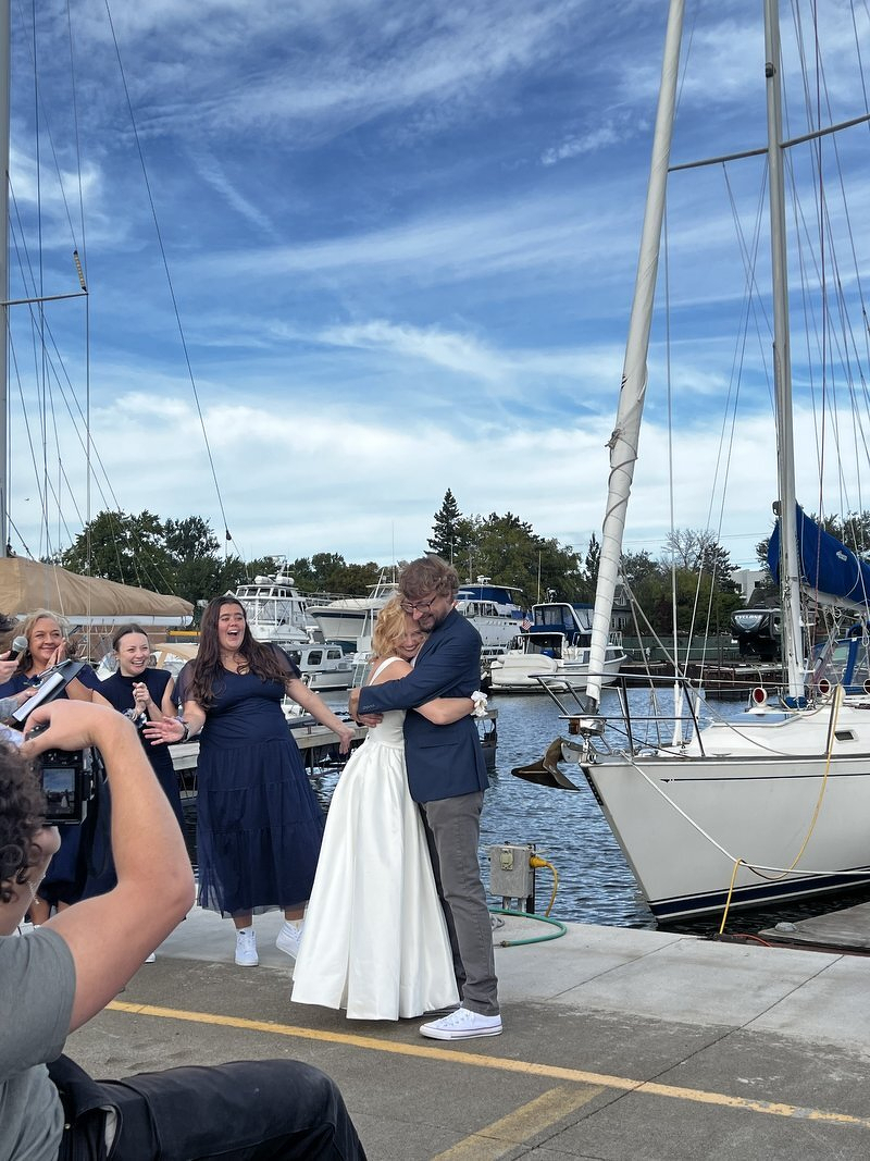 The bride and groom embracing on the dock with sailboats and masts behind them