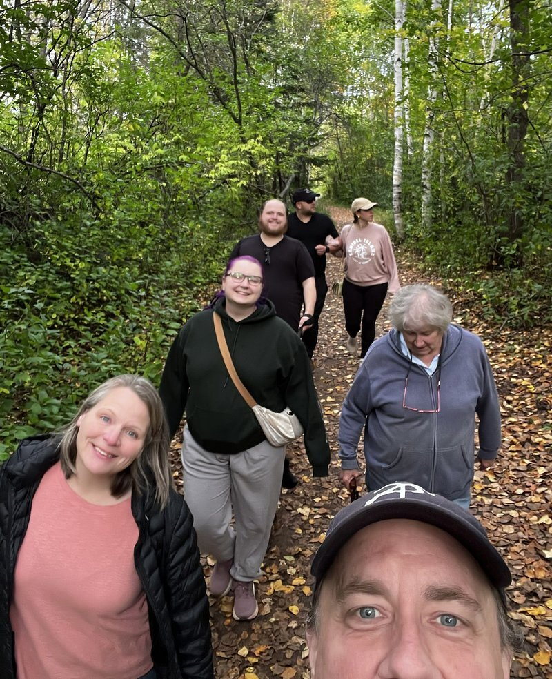 The family walking single file down a leaf-covered trail at Hartley