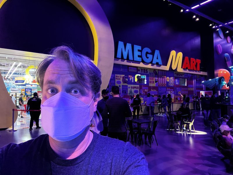 A masked Justin in front of the glowing Mega Mart entrance at Meow Wolf Las Vegas