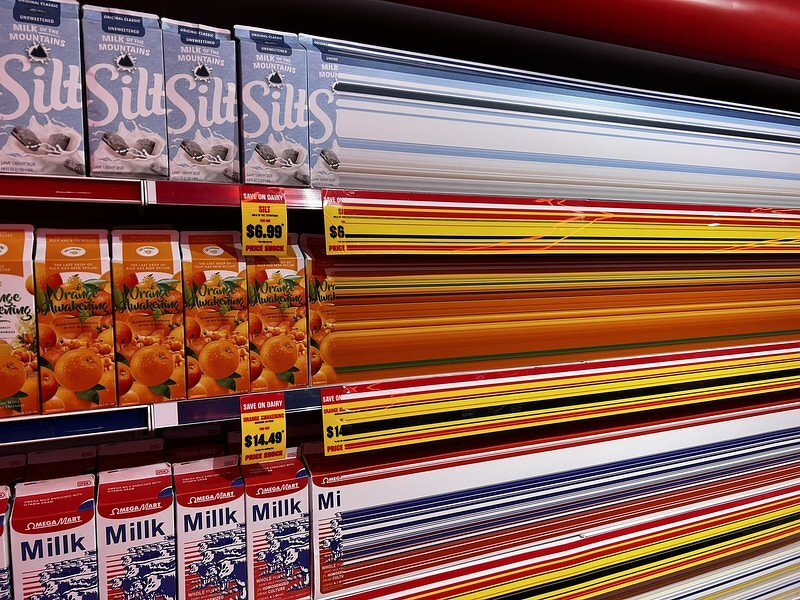 Grocery shelves of milk and juice cartons dissolving into streaks of colored stripes inside the Omega Mart