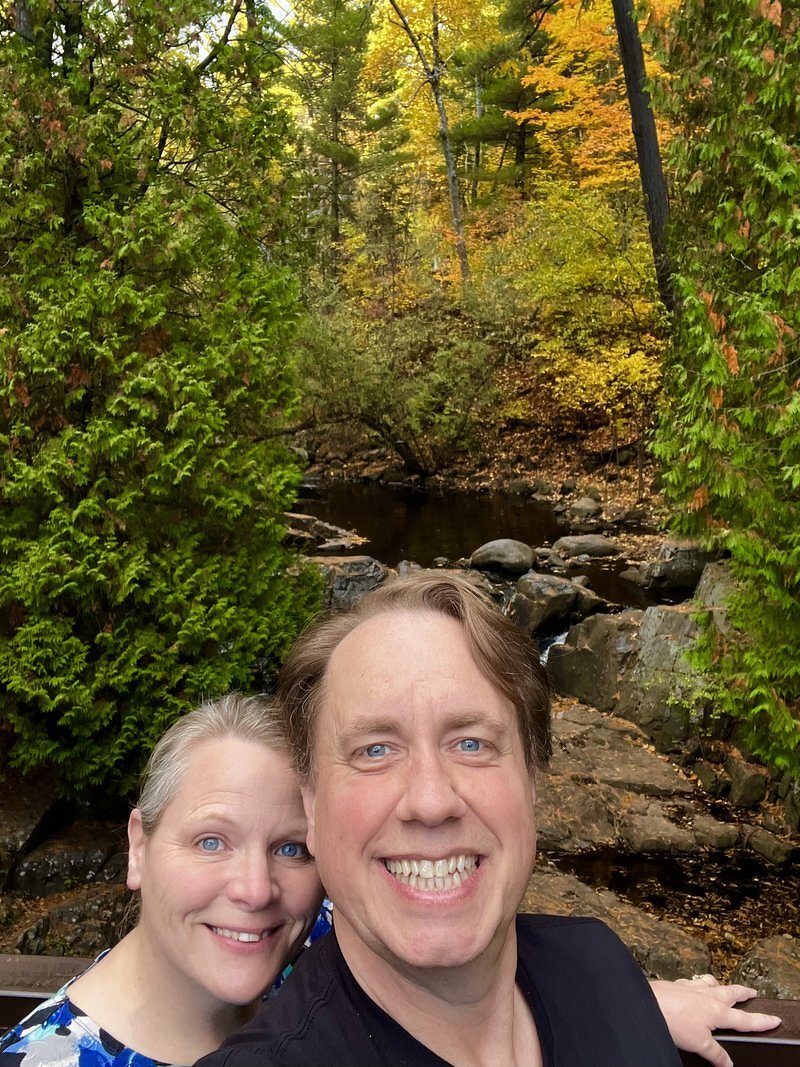 A selfie of Justin and Jody at an overlook above a rocky creek gorge, framed by evergreens