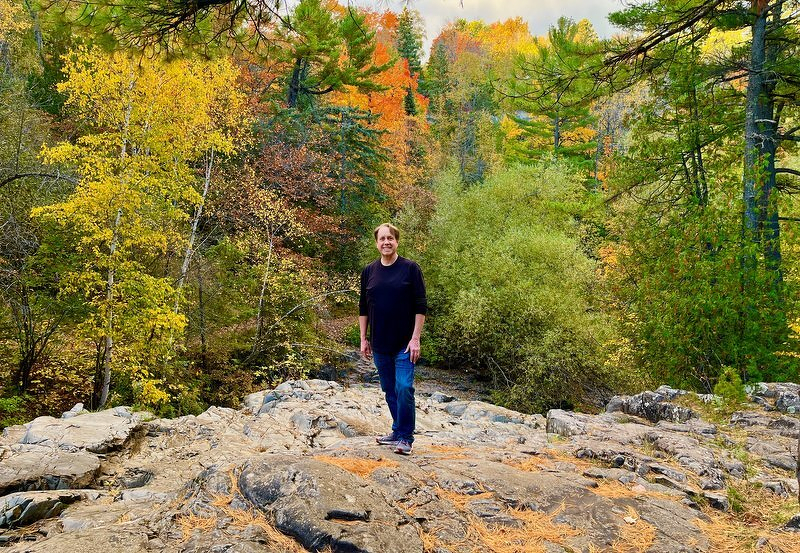 Justin standing on a broad rock outcrop surrounded by yellow and orange trees