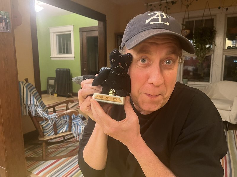 Justin cradling the First Purr-ize trophy, a little black cat statue, against his cheek