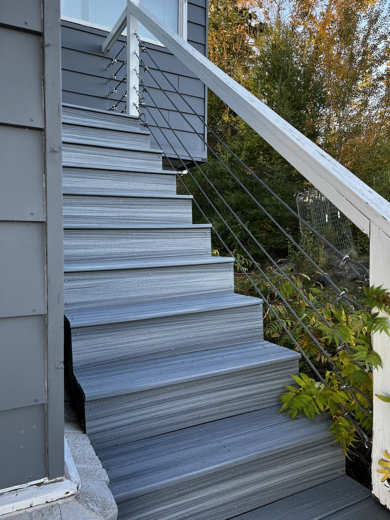 The finished stairs, with new gray composite treads and risers climbing alongside the house