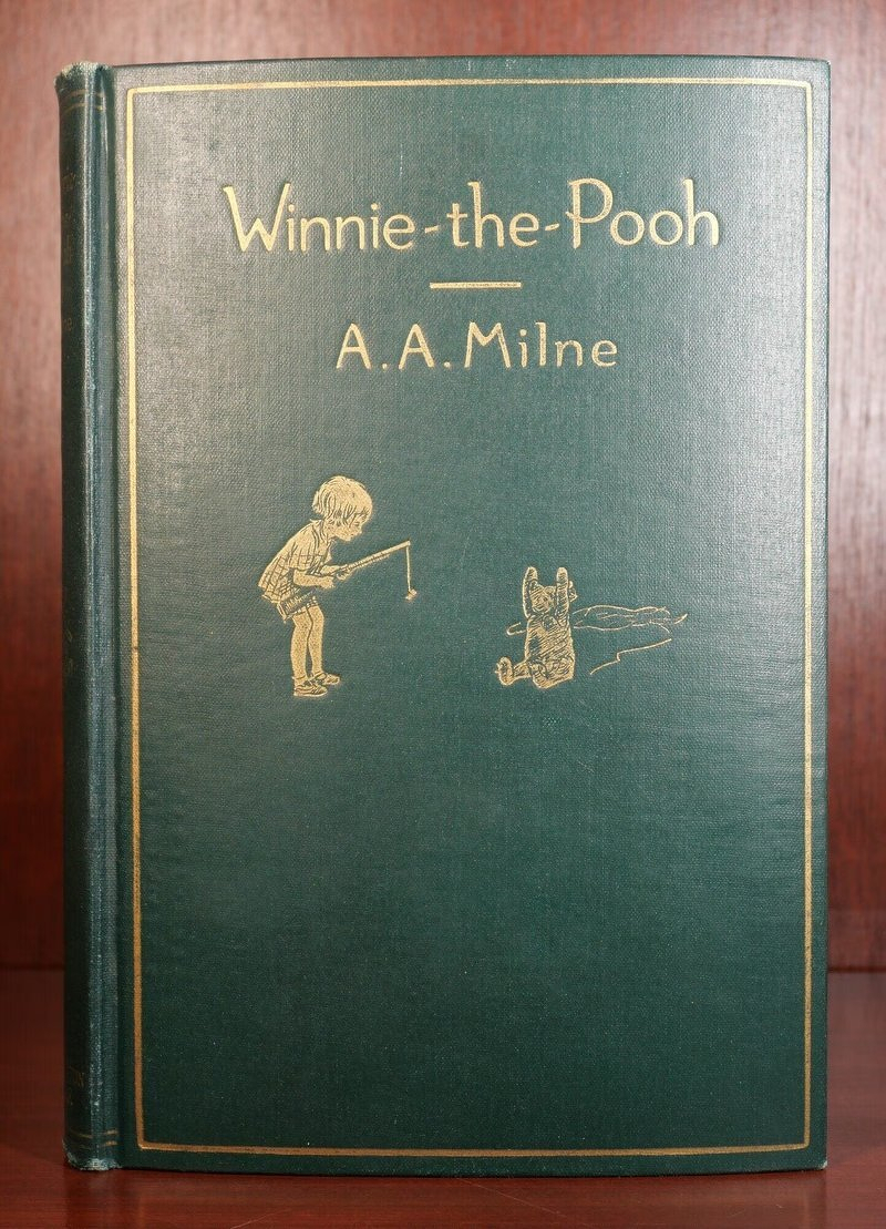 A green clothbound first edition of Winnie-the-Pooh by A.A. Milne, with gilt lettering and a small gold illustration of Christopher Robin and Pooh