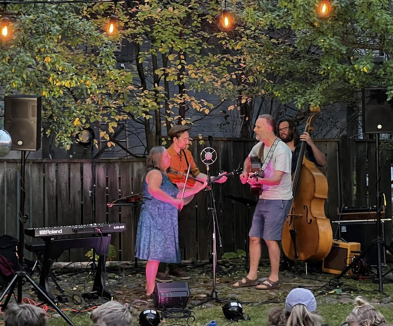 Four Mile Portage and an upright bass player performing on the lawn beneath strings of glowing bistro lights