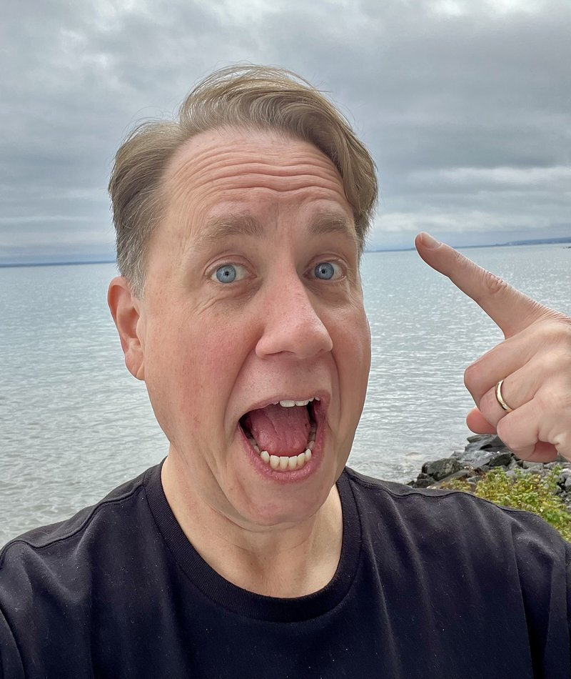 Justin pointing at his fresh haircut with Lake Superior behind him