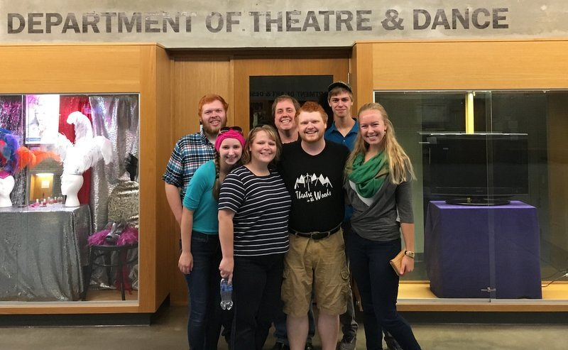 Family and friends gathered with Spencer beneath a Department of Theatre & Dance sign