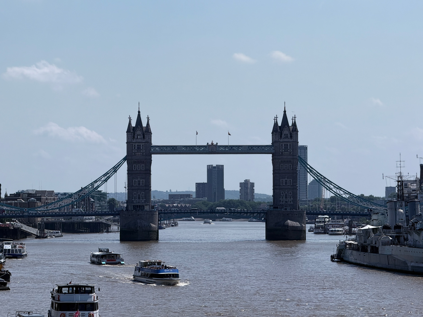 Tower Bridge spans the River Thames with several boats cruising along the water.