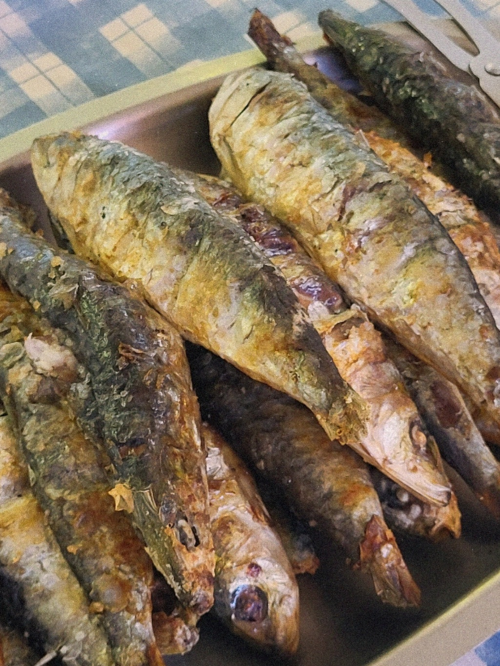 A plate is filled with several grilled whole fish, showcasing their crispy, browned skin.