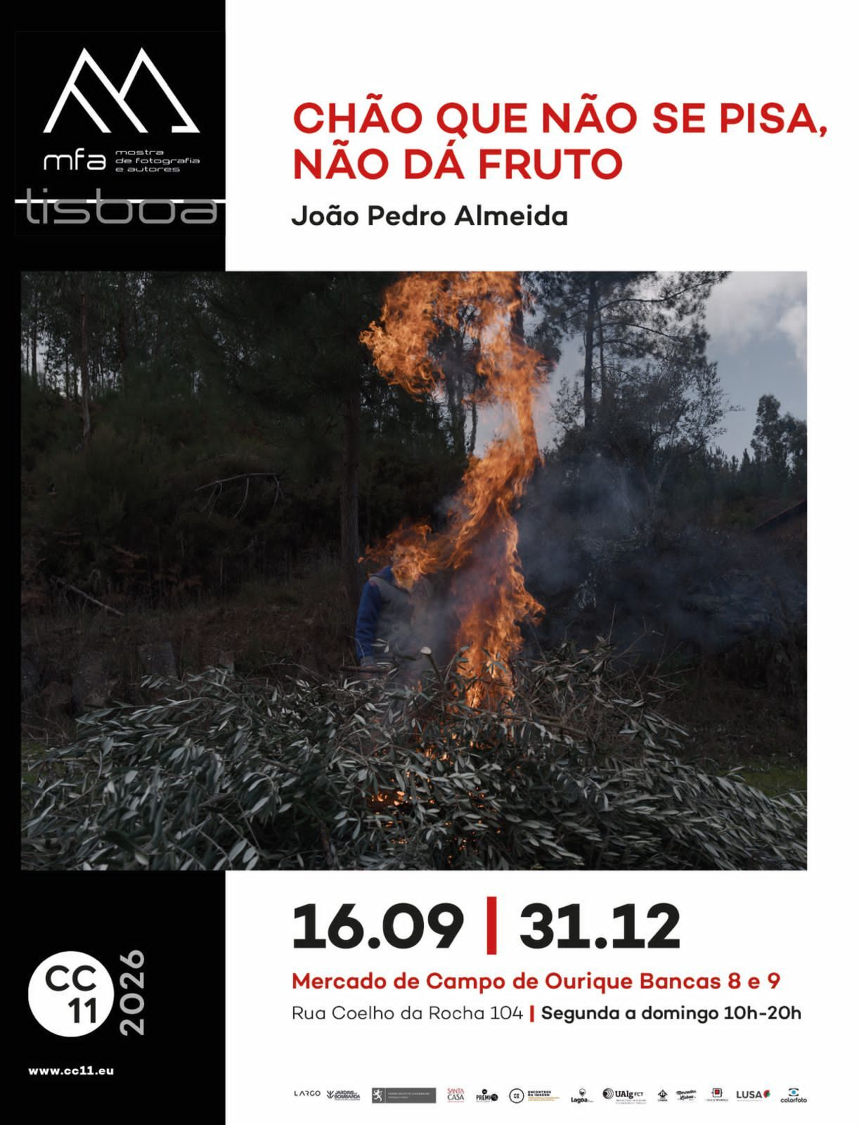 A person tends to a large fire burning in a forested area under an exhibition titled Chão que não se pisa, não dá fruto by João Pedro Almeida.