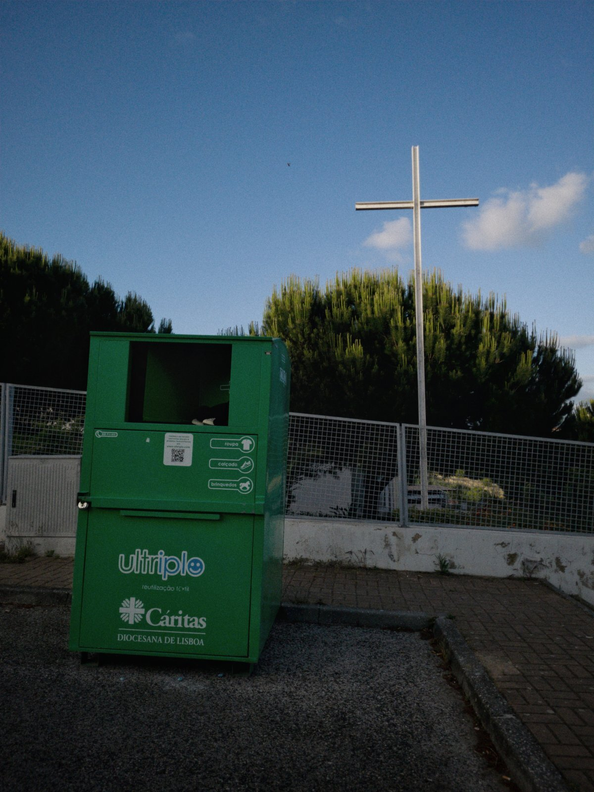 Cross near tree and and used clothing container 