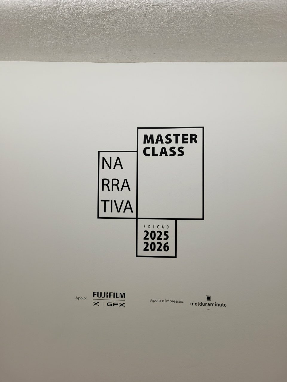 A wall displays text promoting a Narrativa Master Class event for 2025-2026, supported by Fujifilm and molduraminuto.