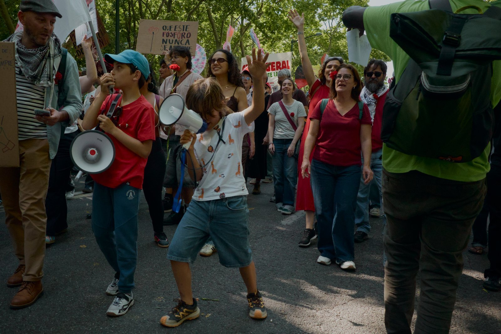 A group of people, including children with megaphones, is energetically participating in a protest or demonstration.
