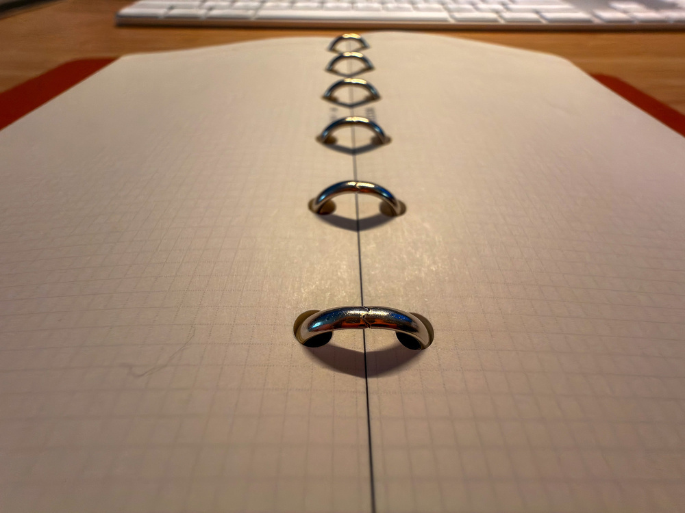 A ring binder notebook with grid paper is open on a desk, with a keyboard in the background.