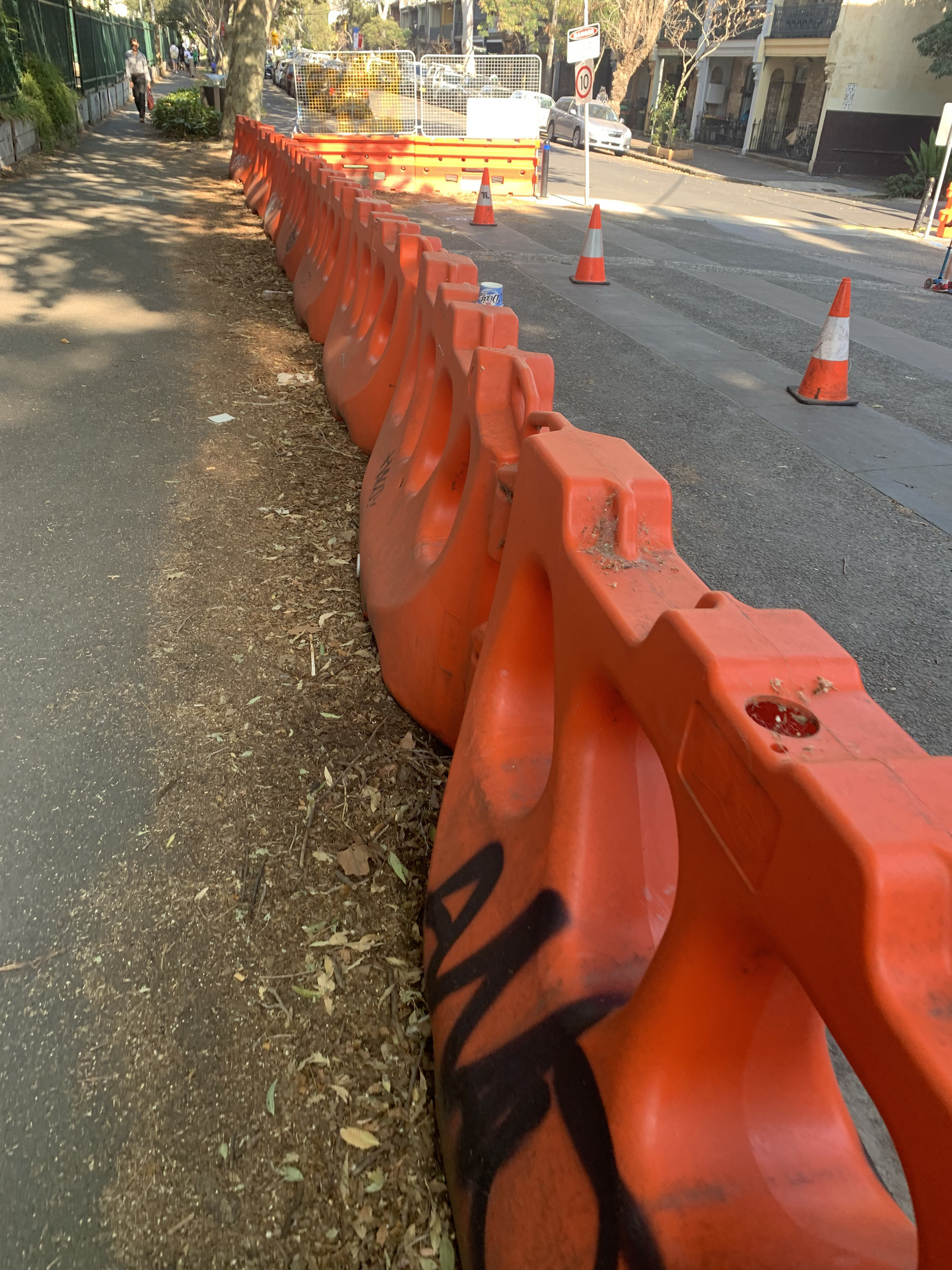 A line of orange road barriers used to set aside a construction area that is normally available for parking