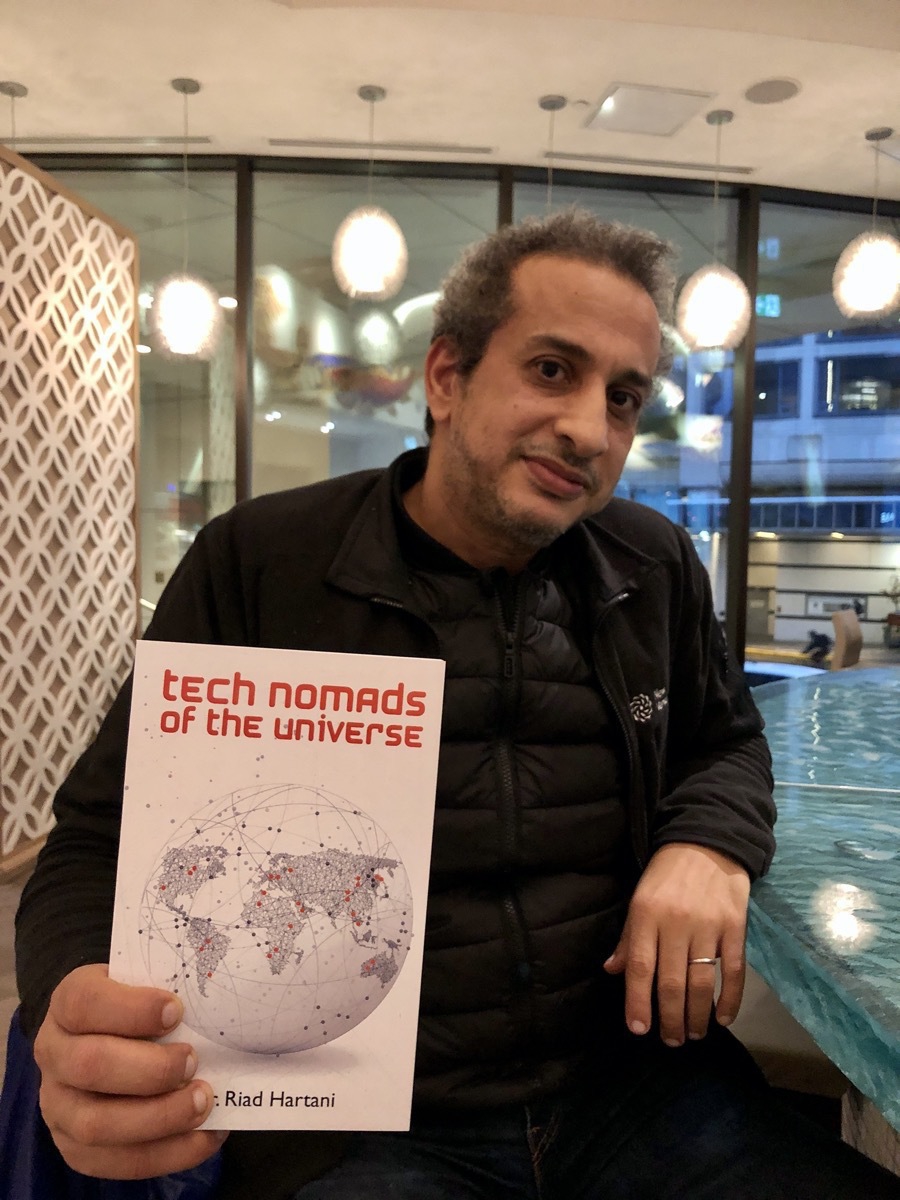 Riad Hartani holding Tech Nomads of the Universe book