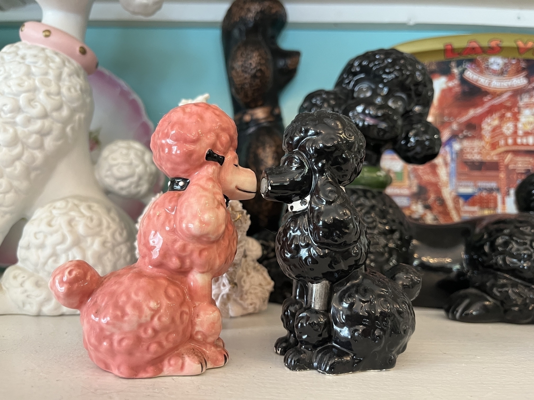 Close up of pink and black ceramic poodle salt and pepper shakers, nose to nose. 