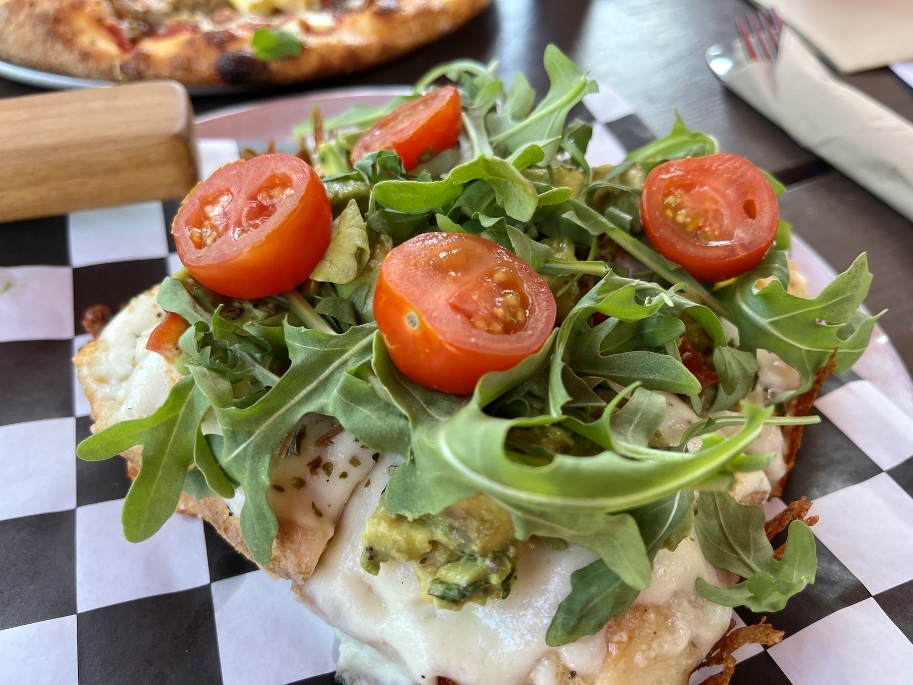 Avocado toast — smashed avos covered in arugula and cherry tomatoes on top of cheese & Detroit pizza crust 