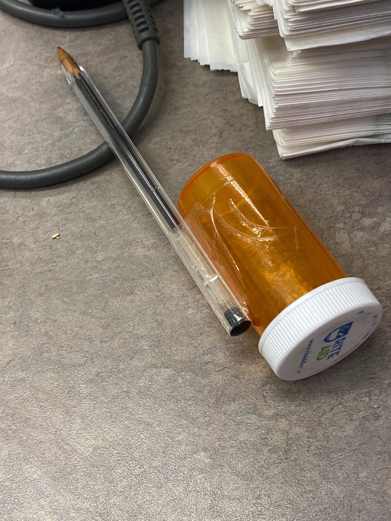 A Pen with an empty pill holder taped to it.