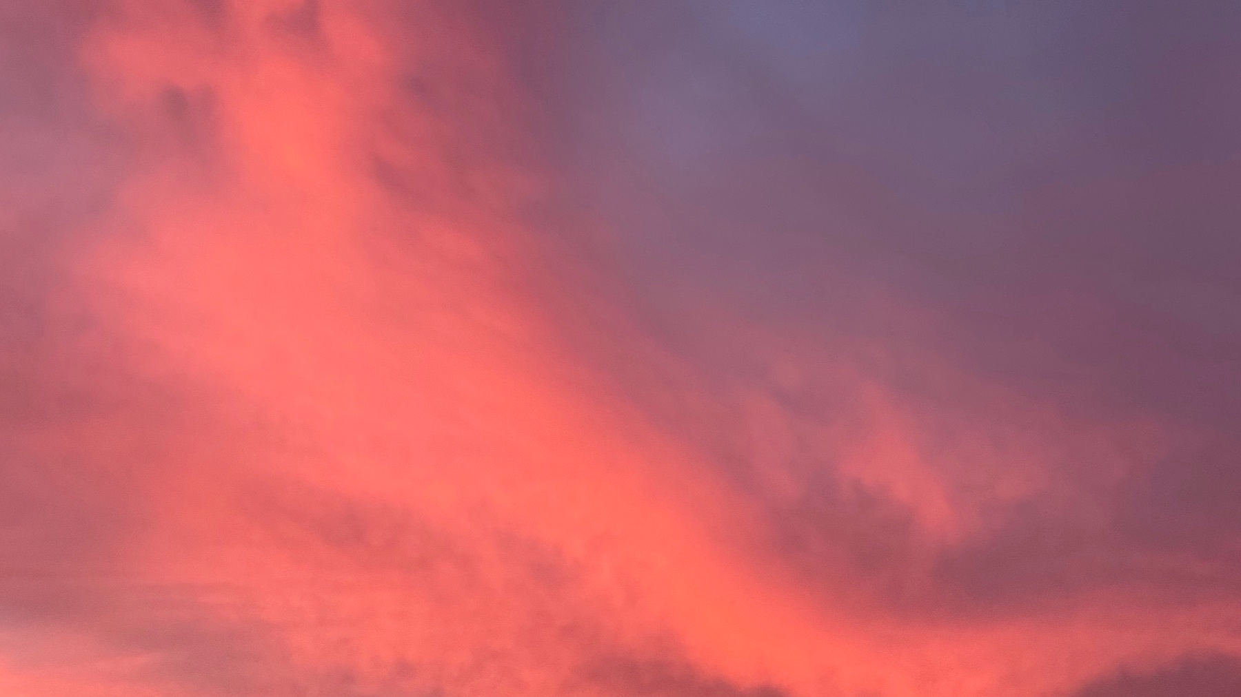 A dramatic sky is filled with pink and purple clouds at dusk.