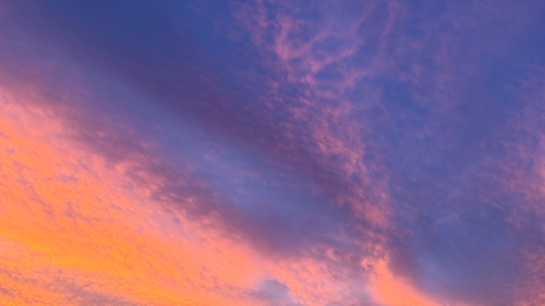 A vibrant sky is filled with soft hues of pink, purple, and orange clouds during sunset.