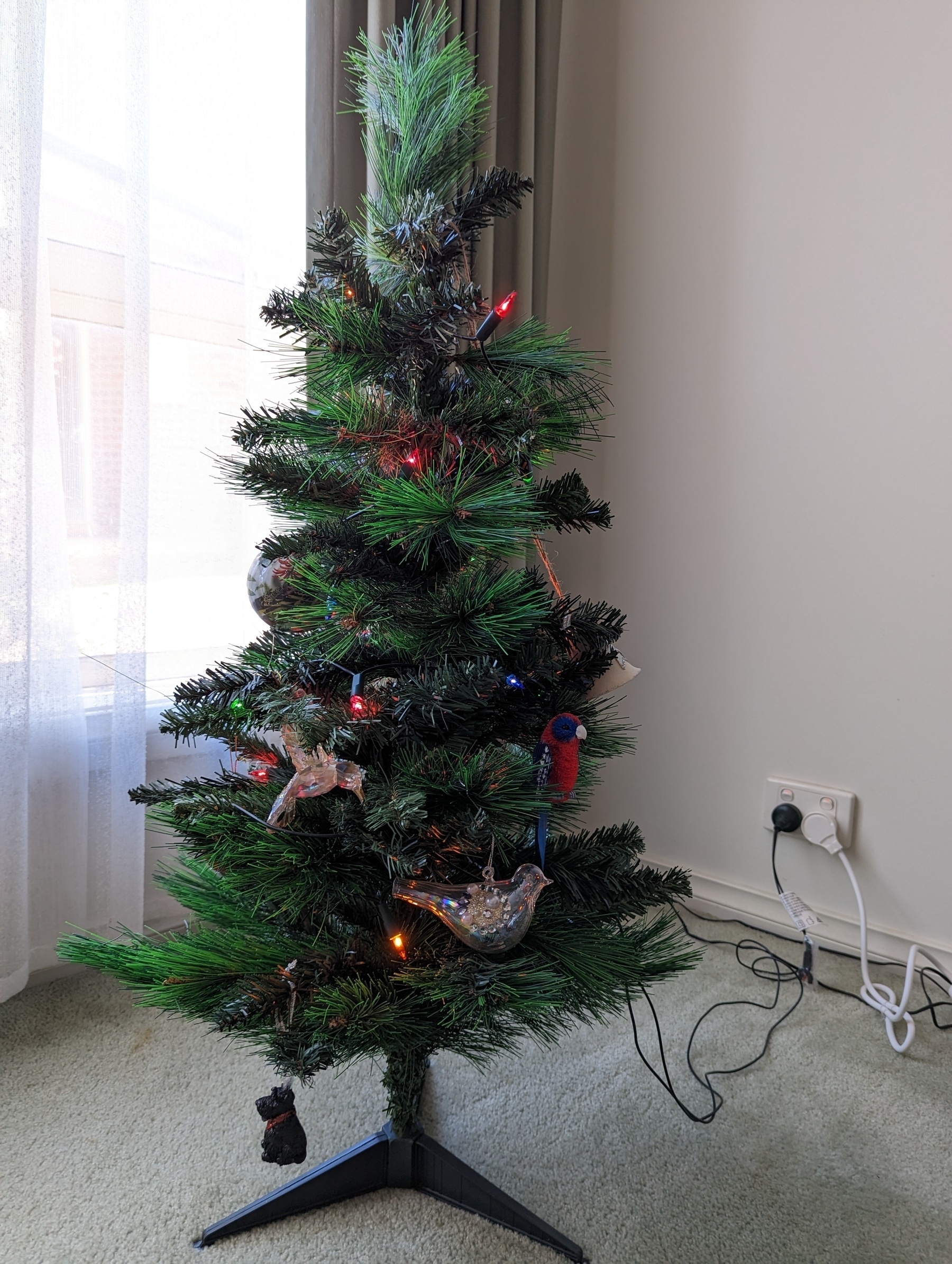 Christmas tree with lights on and a fair few bird ordainments