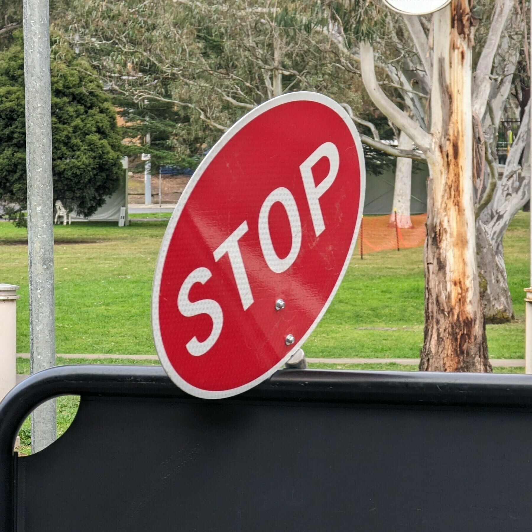 A hand-held stop sign resting on a fence.