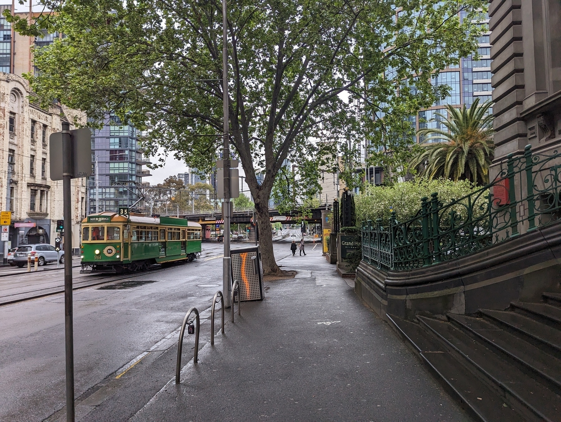 Footpath of Spenser Street looking towards the river, with the hotel on the right and a W-class tram travelling up to Southern Cross