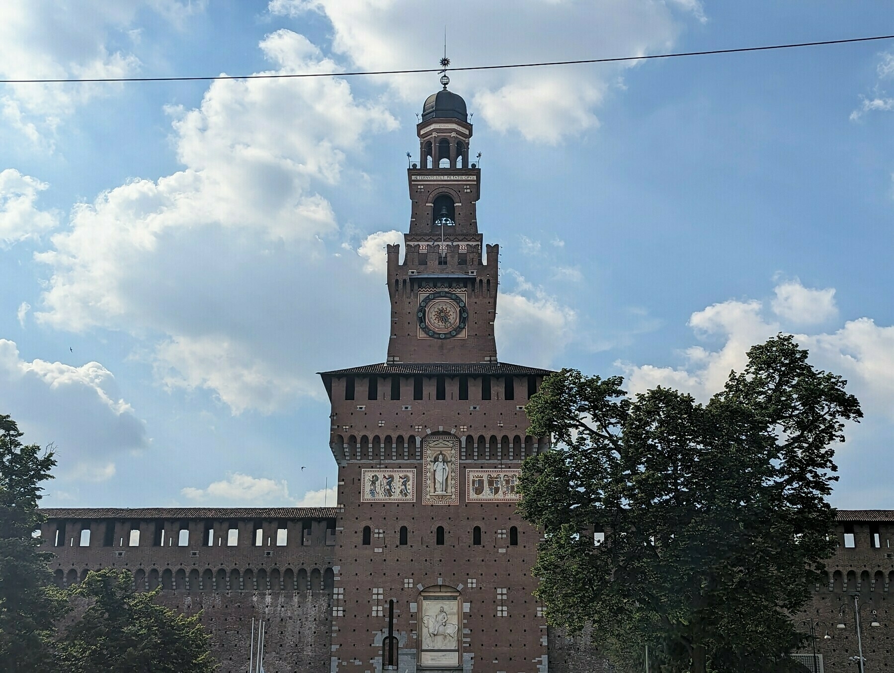 Front of  Castello Sforzesco, a castle, with a large tower above the front gate, with a slightly cloudy sky