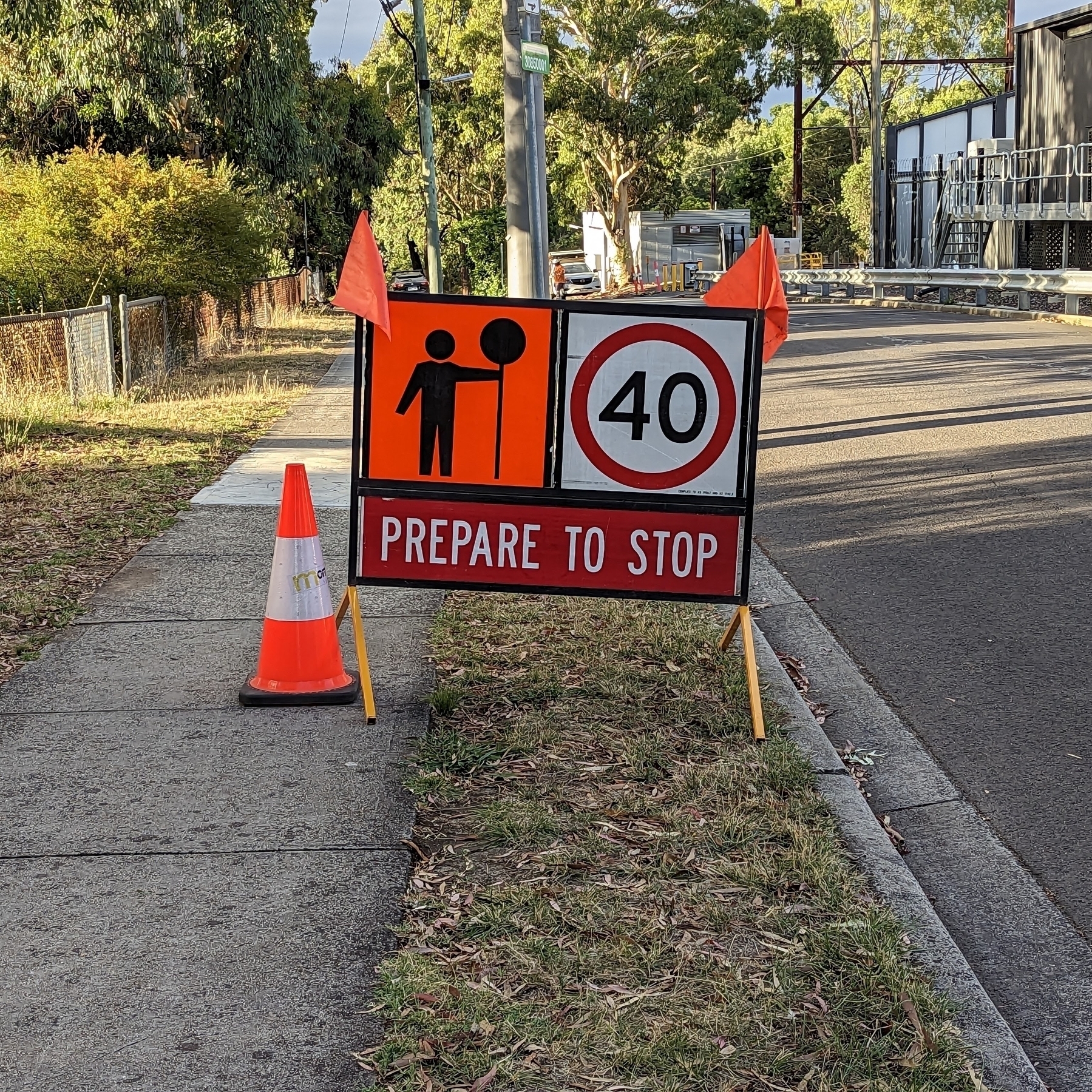 A road works sign with a 40 km/h speed limit, a man holding a stop sign, and the lower portion saying Prepare to Stop