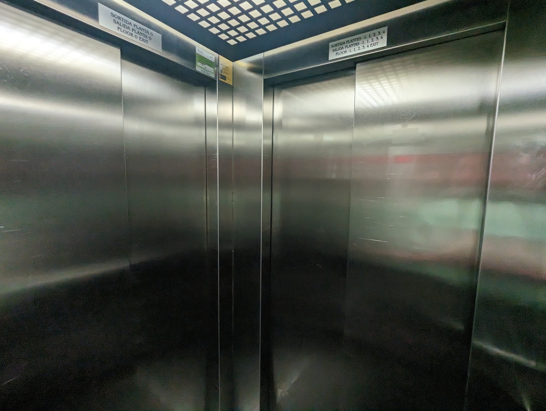 Inside of lift cart with two silver doors next to each other.
