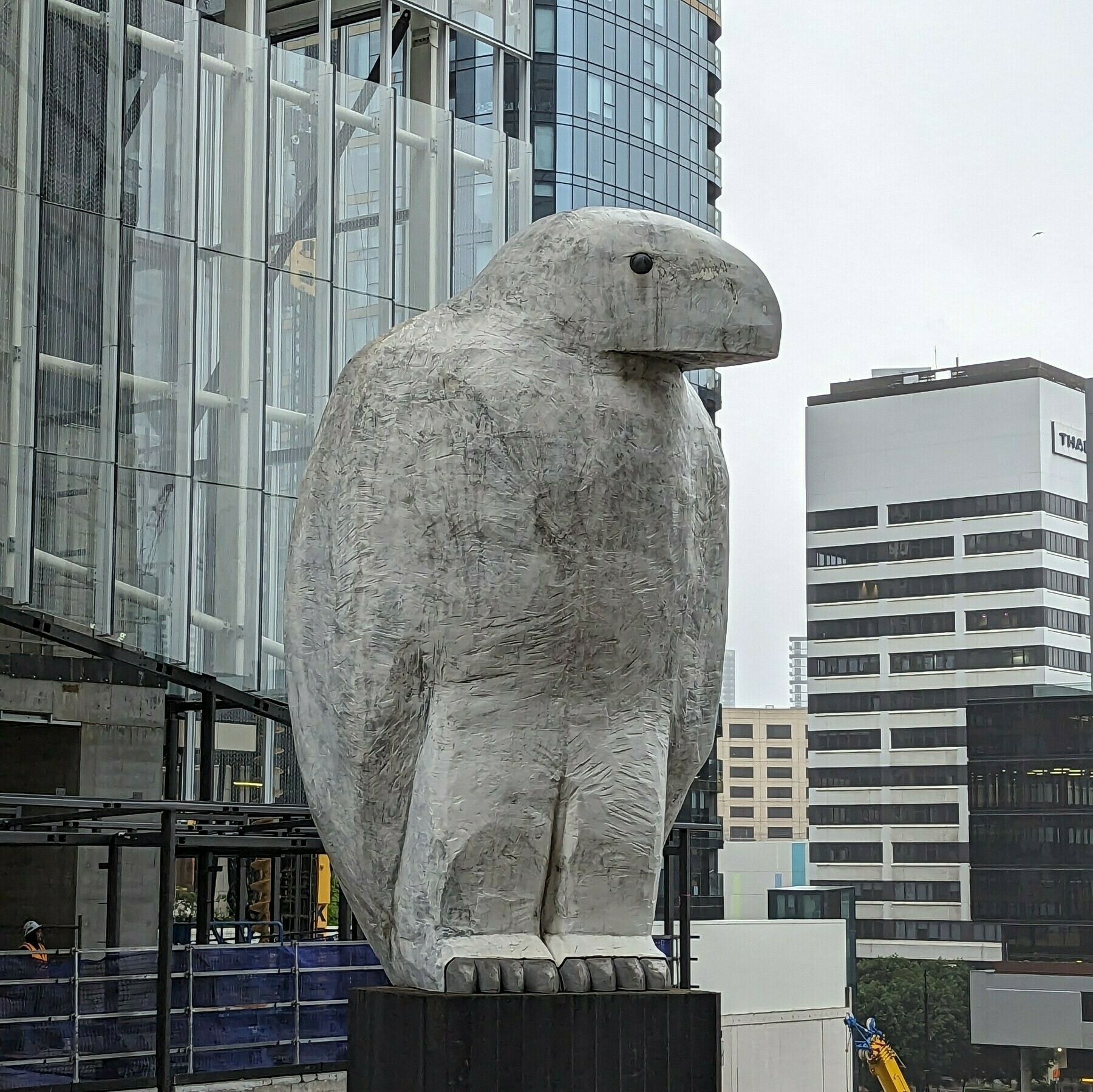 A white, abstract sculpture of an eagle surrounded by buildings