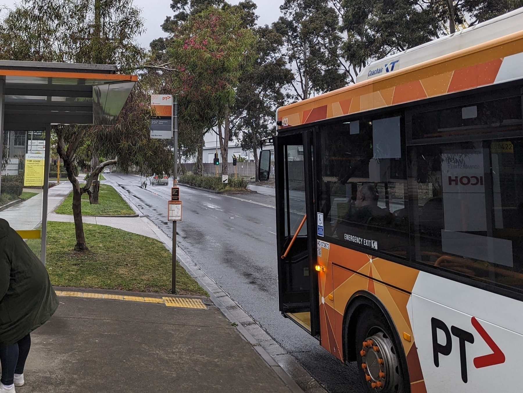 A bus in orange livery at a bus-stop with an orange sign and trim