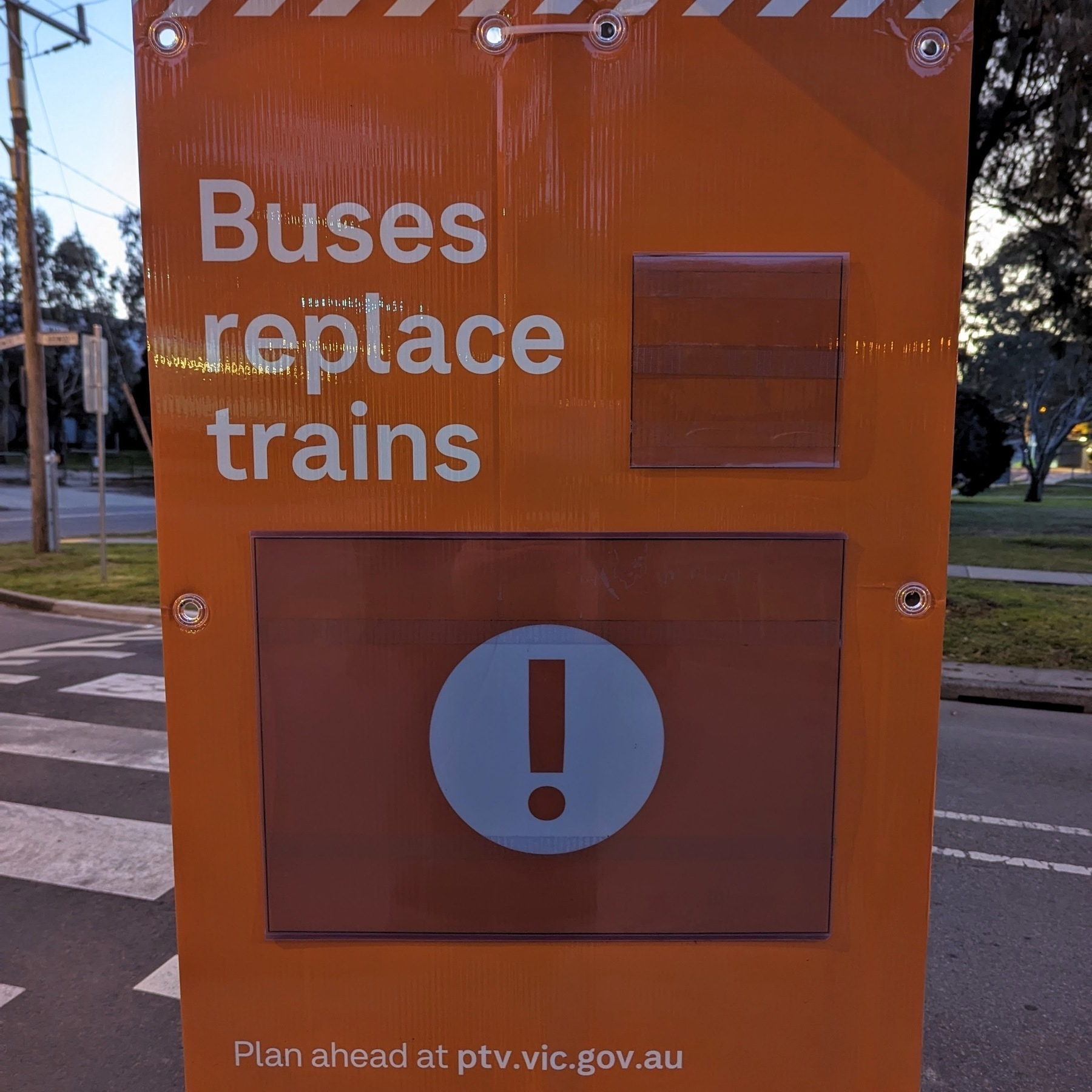 A large orange sign that reads 'Buses replace trains' and then below an exclamation icon reads 'Plan ahead at ptv.vic.gov.au'