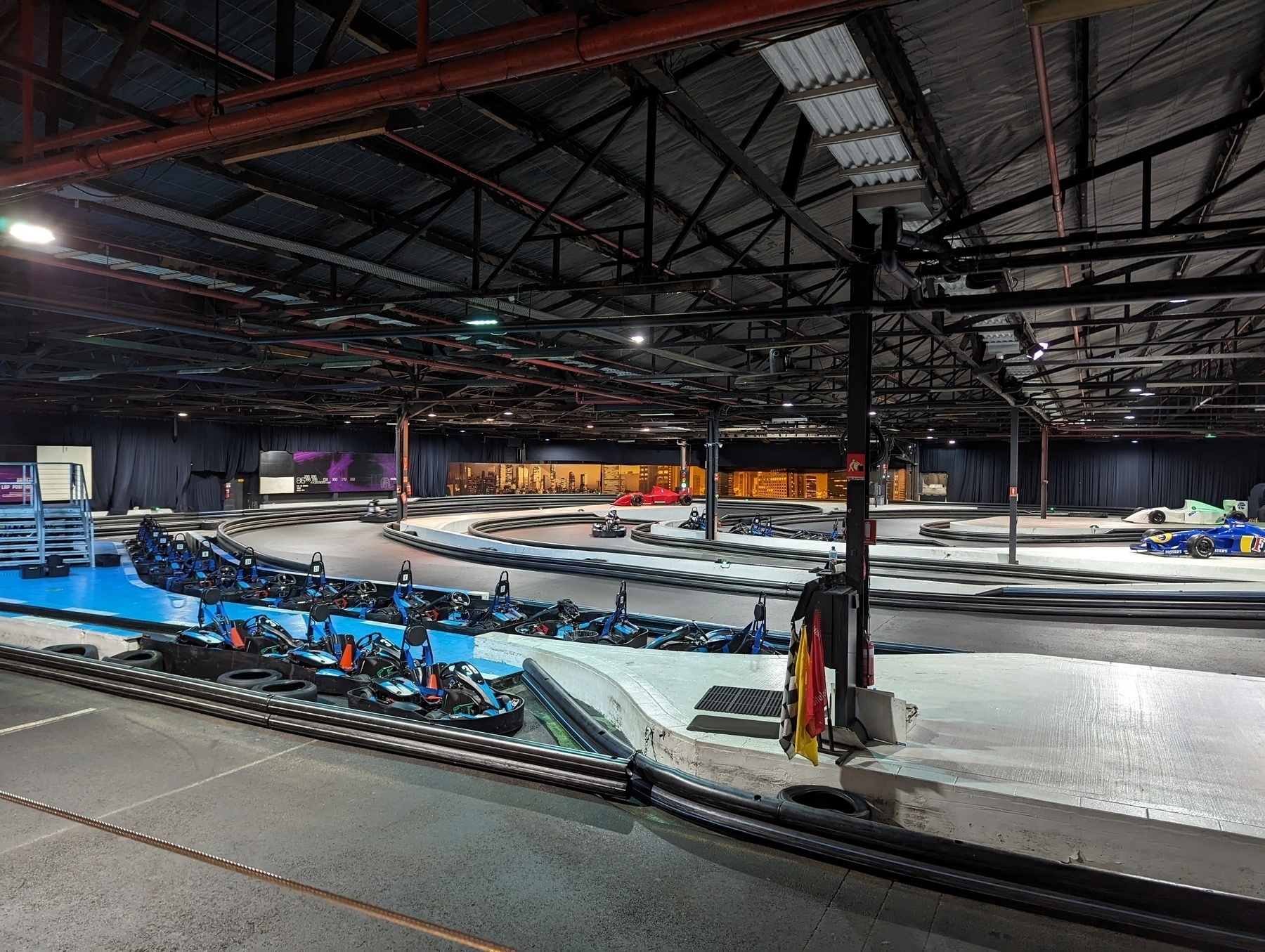 An indoor go-kart track with a couple of karts doing a circuit