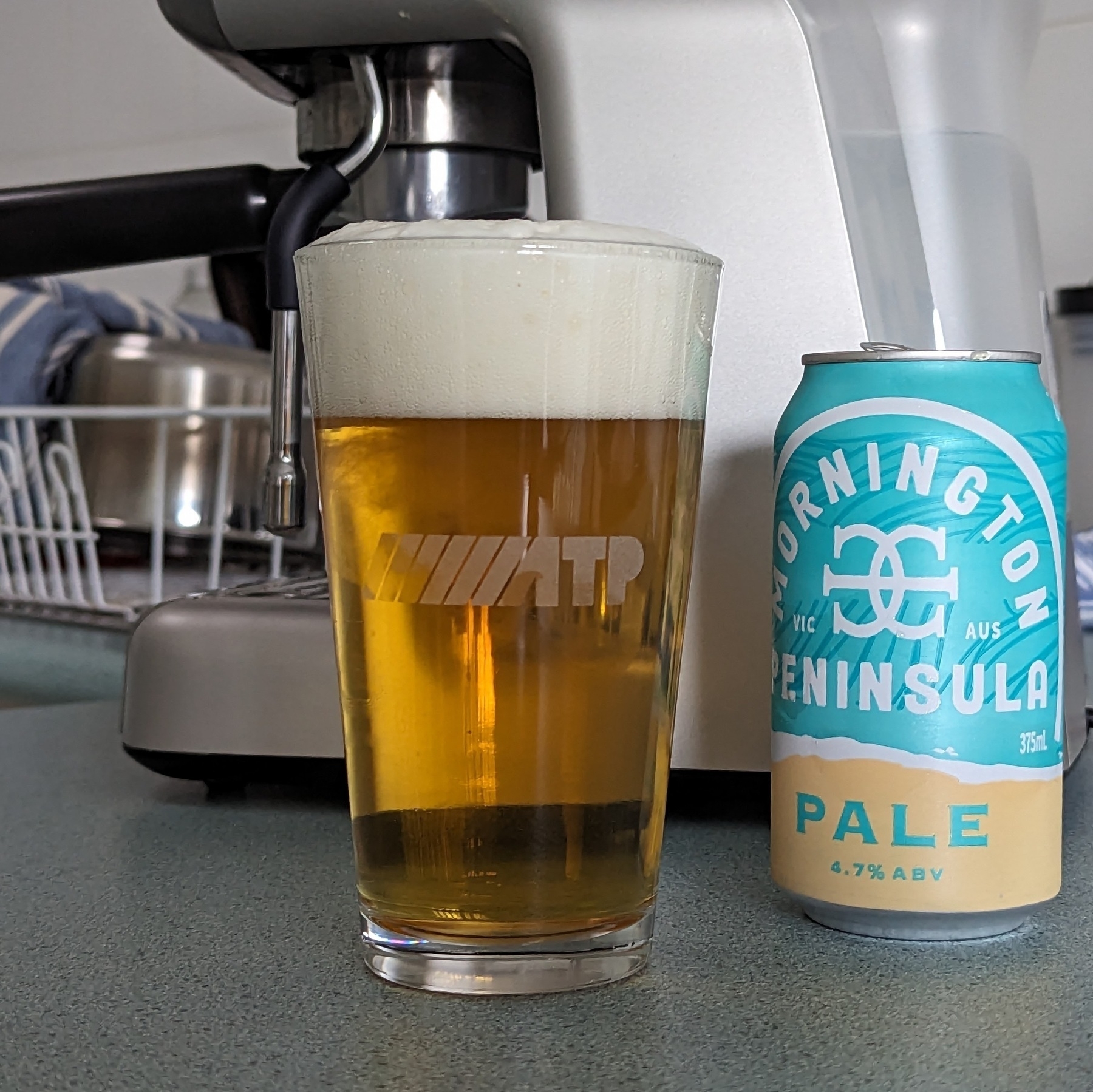 A can of Mornington Peninsula Pale-ale poured into an ATP glass, placed in front of a coffee machine