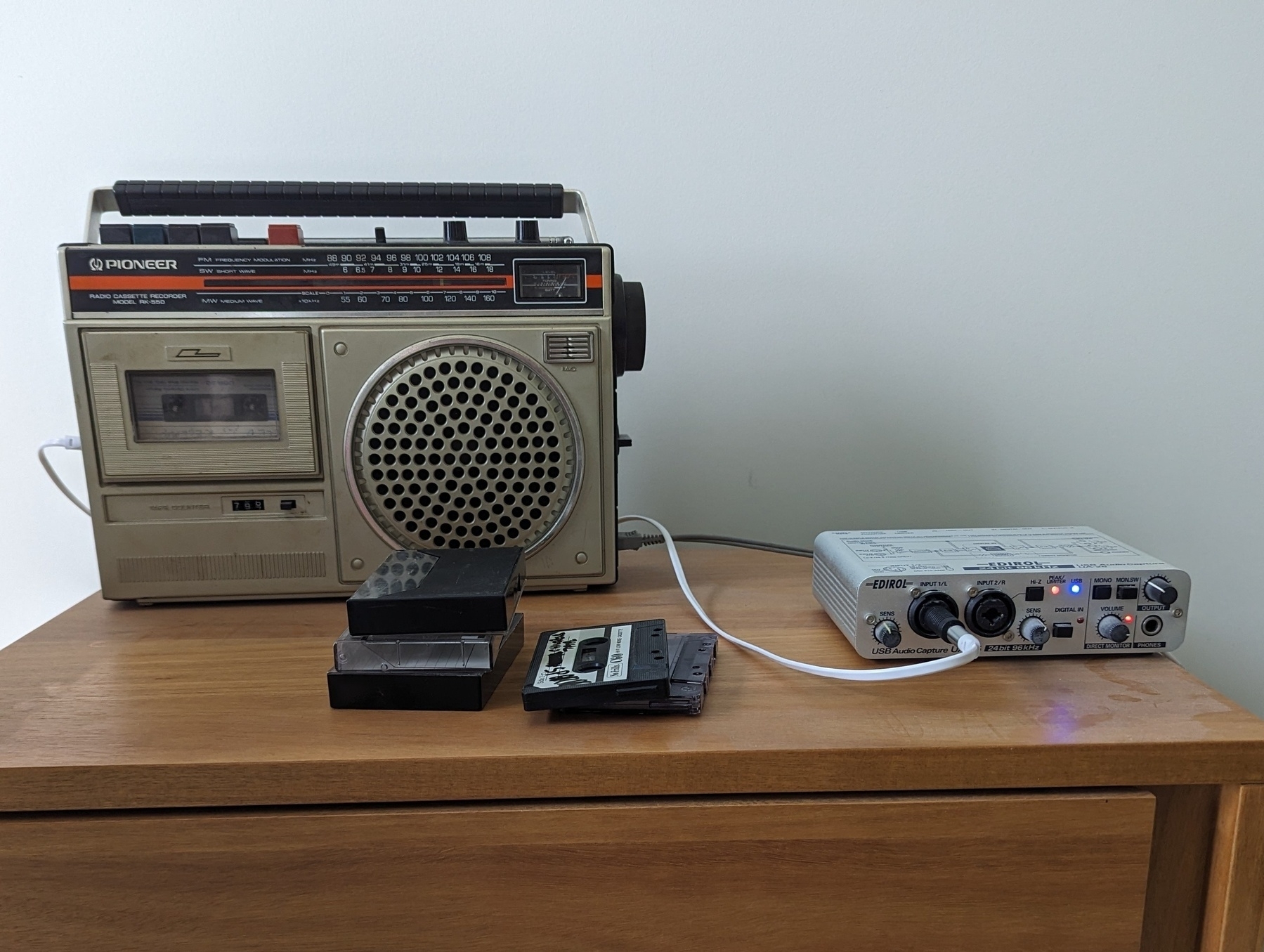 A radio and cassette player connected to a USB interface with a few cassettes in the foreground.