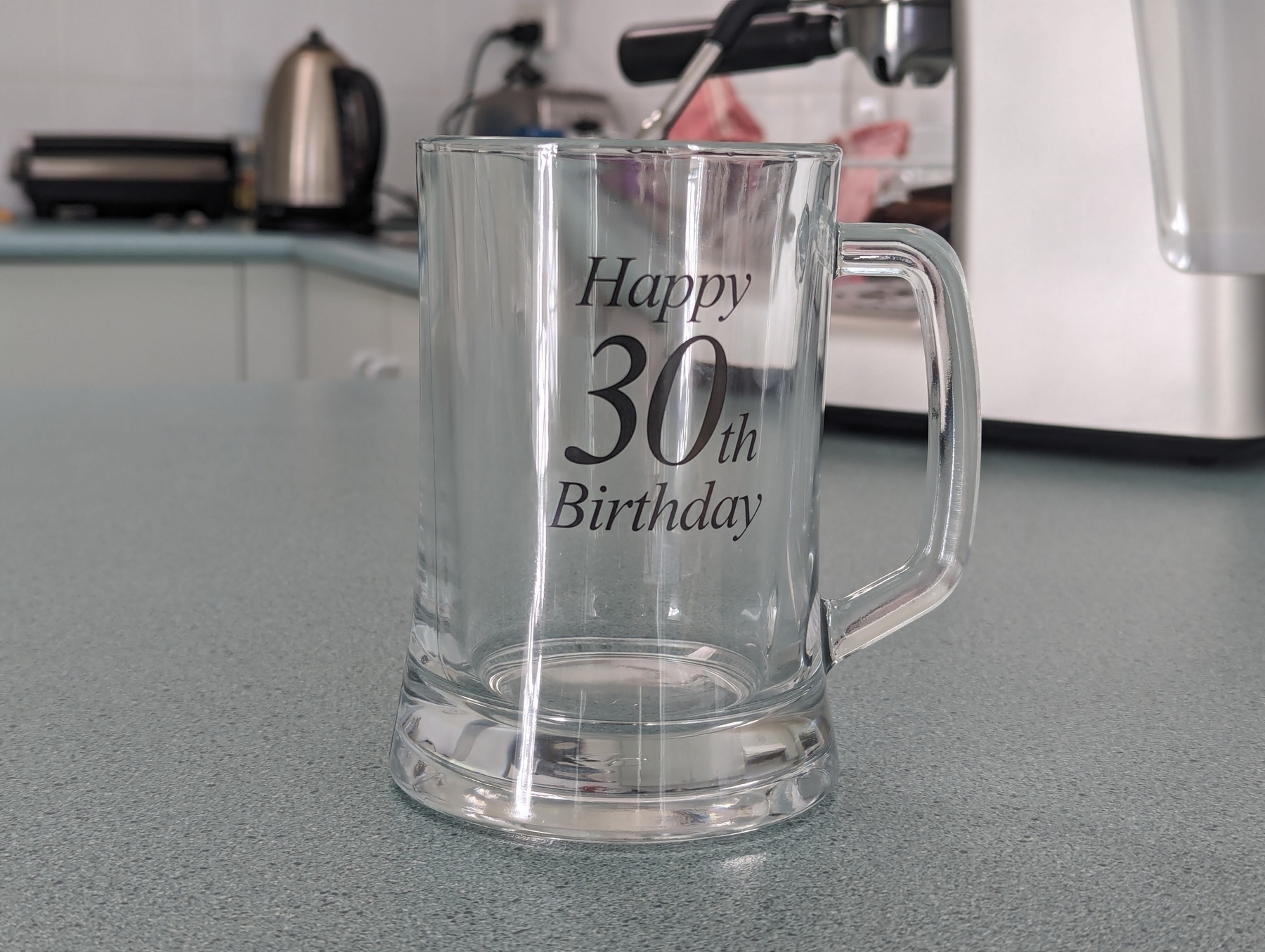 A glass stein on a bench with the inscription "Happy 30th Birthday" written on the front