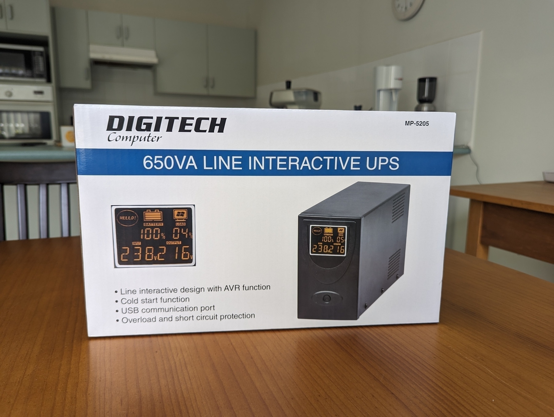 A box containing a Digitech 650VA Line Interactive Uninterruptible Power Supply (UPS) is placed on a wooden kitchen table.