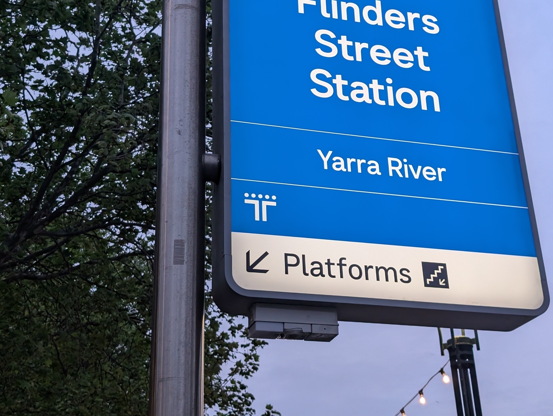 A blue sign indicates directions to Flinders Street Station, Yarra River, and platforms, with the Transport Victoria logo 