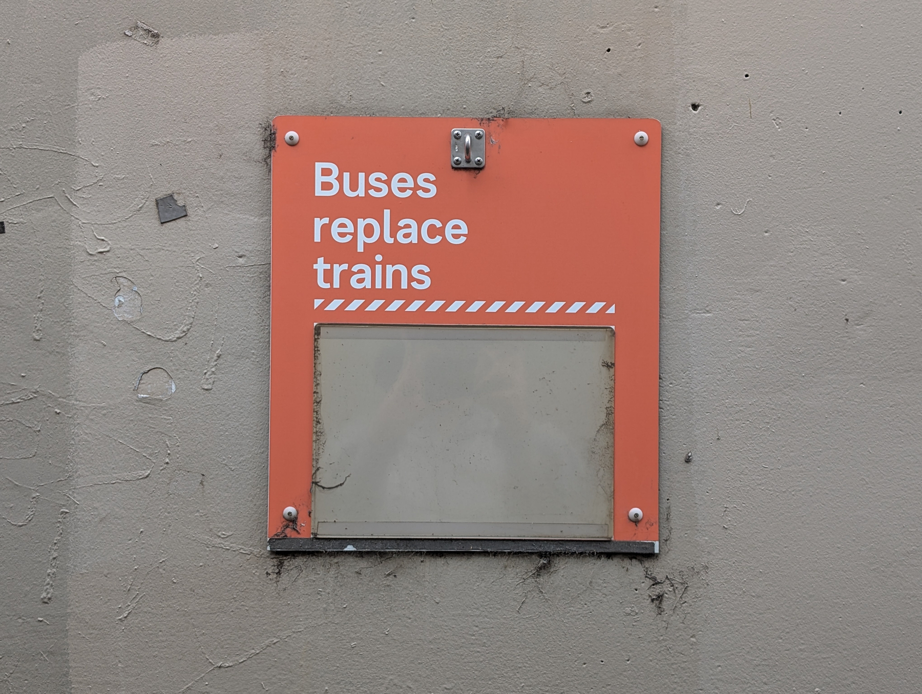 A sign mounted on a wall reads Buses replace trains with an empty space beneath the text.
