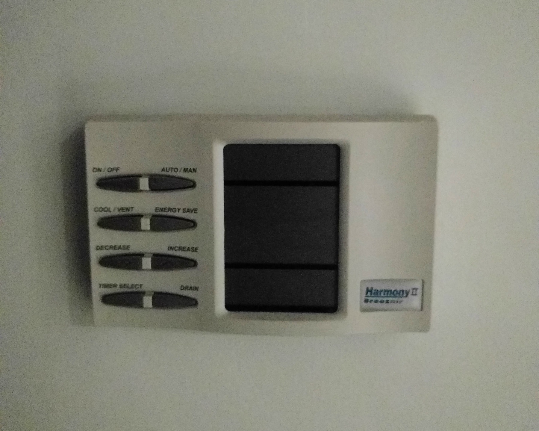 Auto-generated description: A wall-mounted thermostat with buttons labeled for power, mode, and temperature adjustment options.