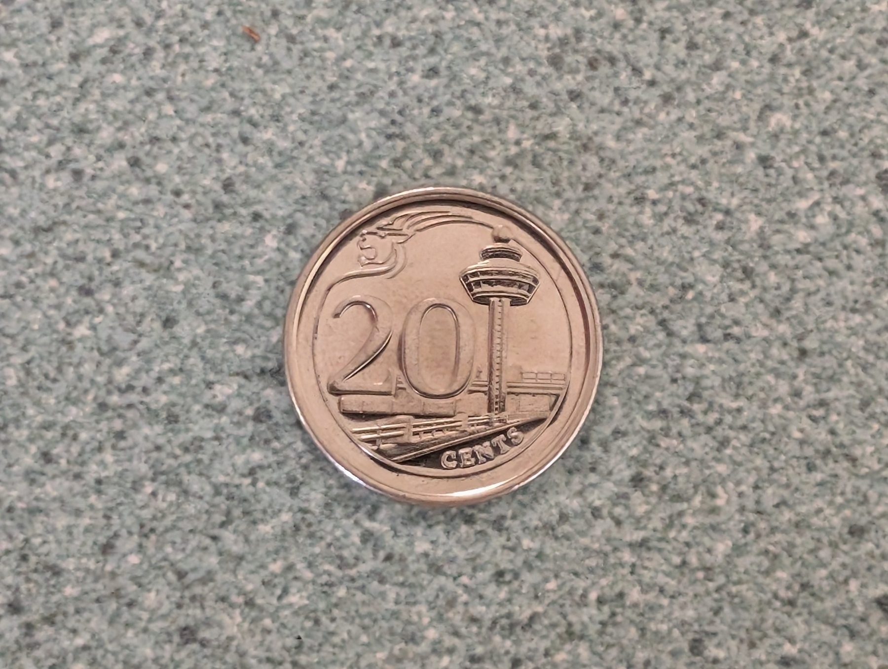 Auto-generated description: A 20-cent coin from Singapore features a distinctive tower design on one side.