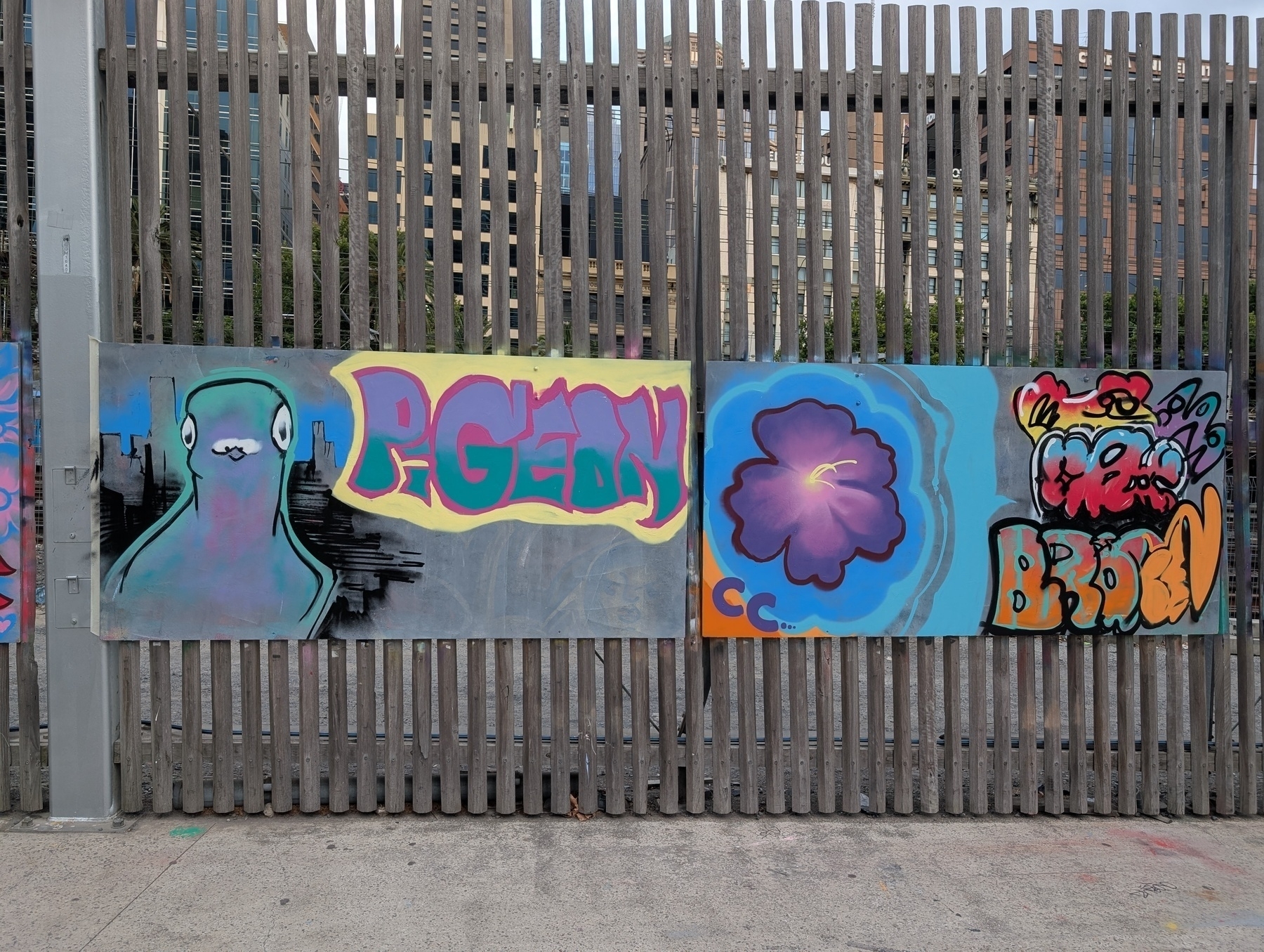 Auto-generated description: Vibrant street art featuring abstract designs and colourful graffiti is displayed on panels attached to a wooden fence.